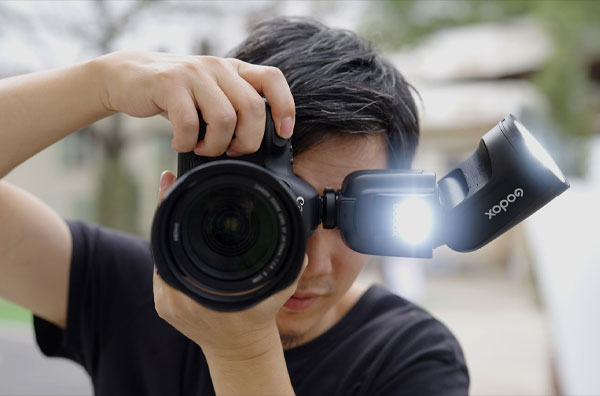 فلاش اسپیدلایت گودکس Godox روی دوربین و مرد در حال عکاسی